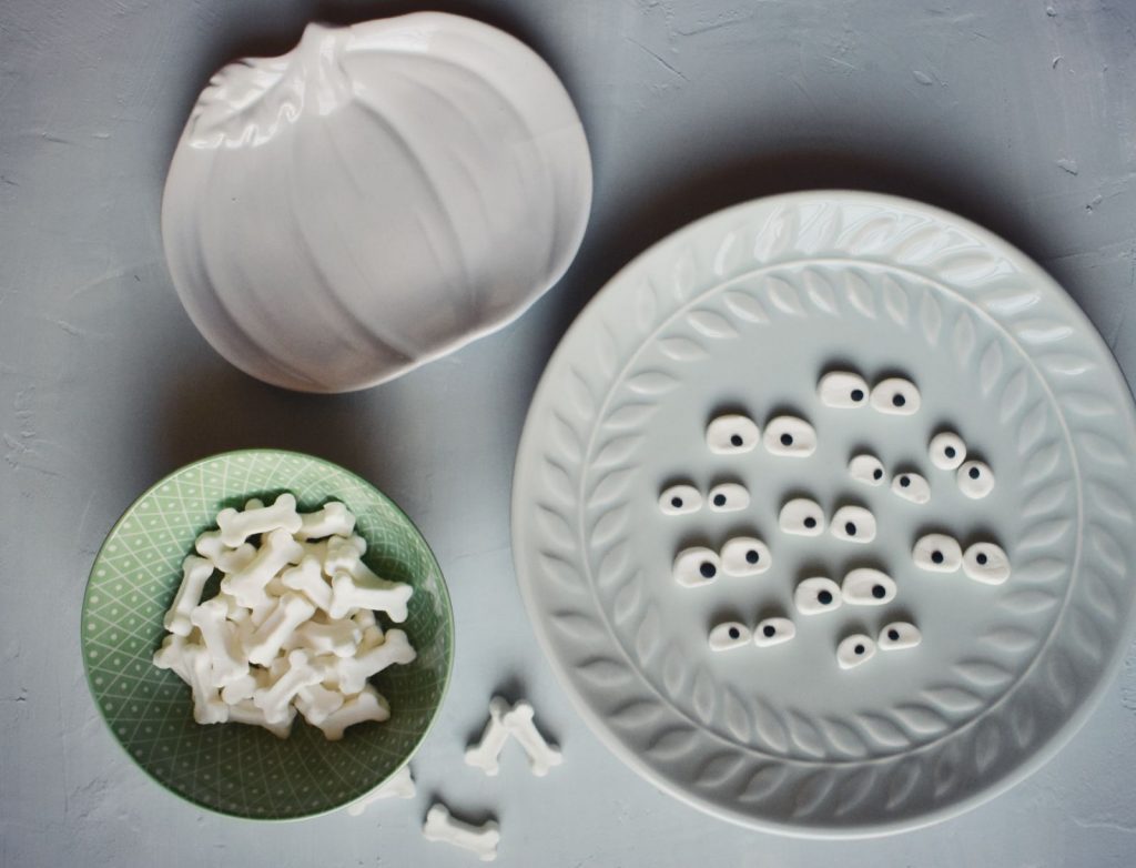 Candy bones and candy eyeballs on a decorative seafoam plate and a sage green dish