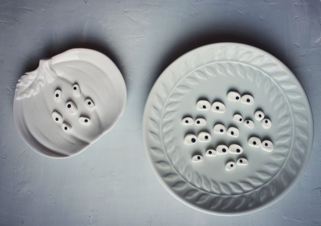 Candy eyeballs on a ceramic pumpkin shaped plate and a decorative dish
