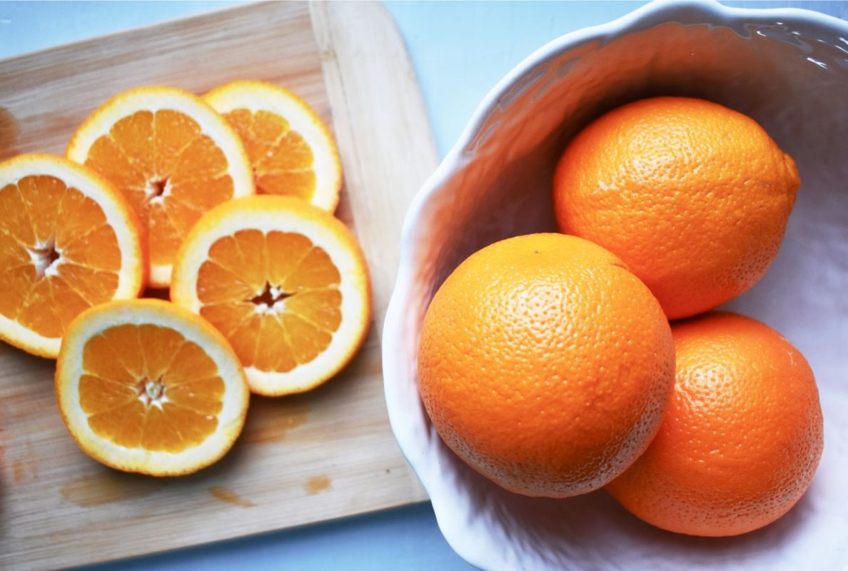 A bowl of fresh oranges with orange slices
