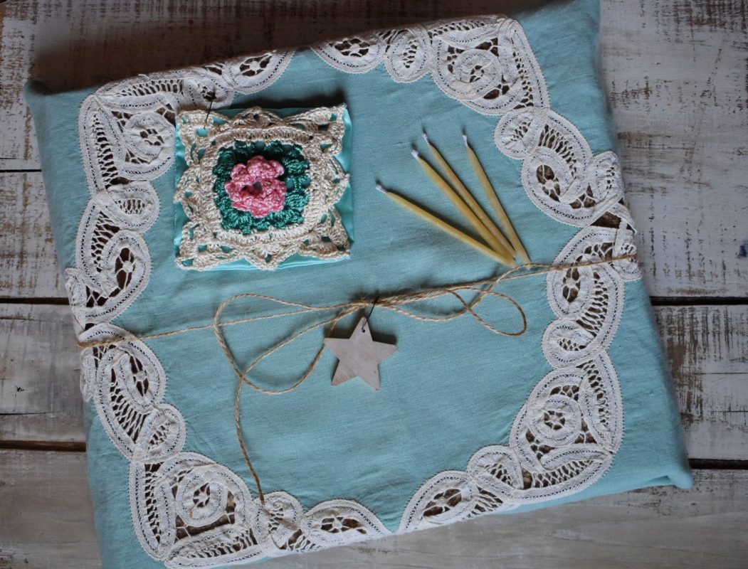 A gift wrapped with a seafoam green and white lace vintage tablecloth